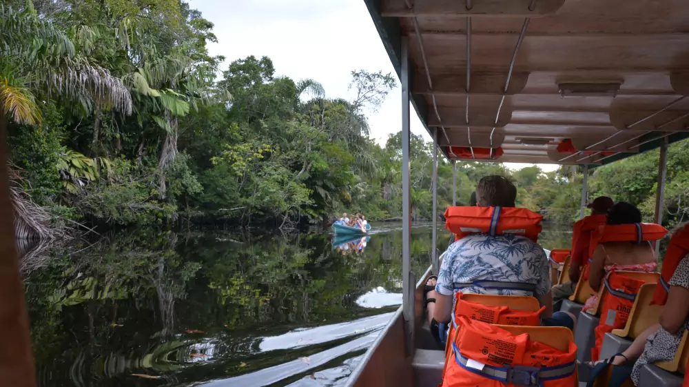 Passagers en gilet de sauvetage sur un canal, une petite barque devant eux