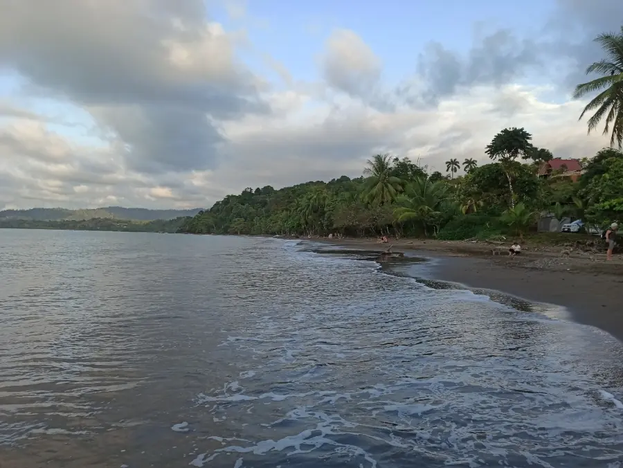 Playa Negra à Puerto Viejo : sable sombre, cocotiers et mer calme sous les nuages