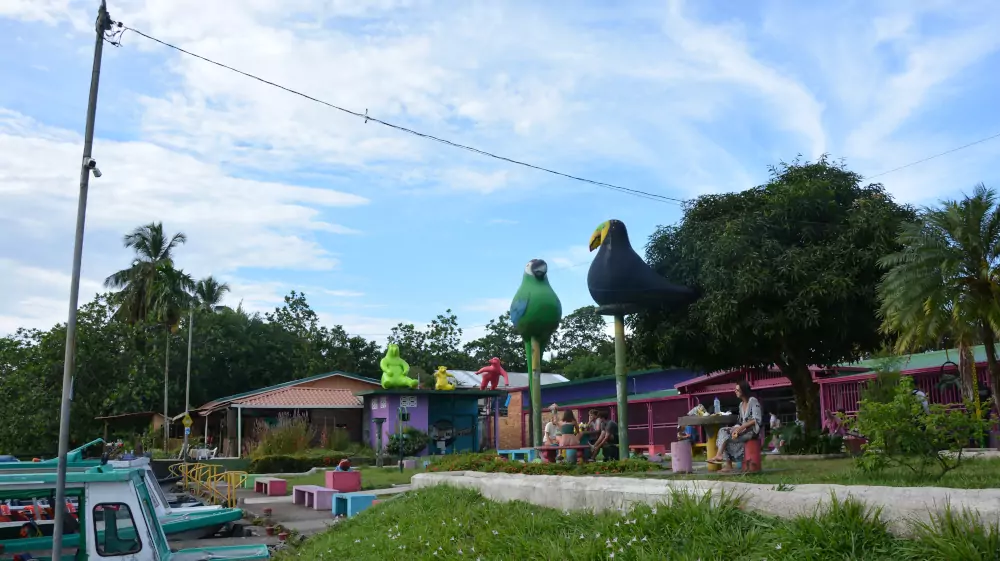 Le quai du village de Tortuguero, ses bateaux et ses grandes sculptures d'oiseaux colorées