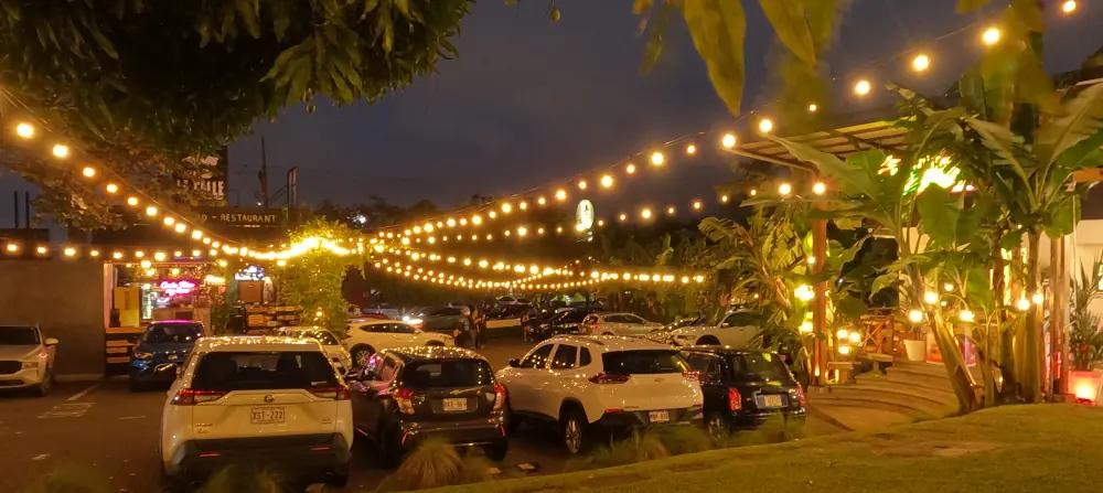 Restaurants autour d'un parking décoré de guirlandes lumineuses, le soir