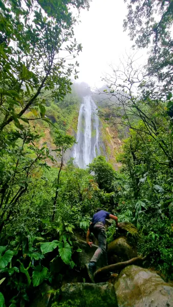 Un homme grimpe sur les rochers de la forêt vers la cascade de Las Lajas