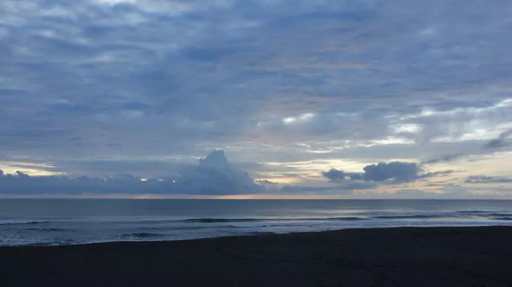 Plage de sable sombre sur la mer des Caraïbes au coucher du soleil