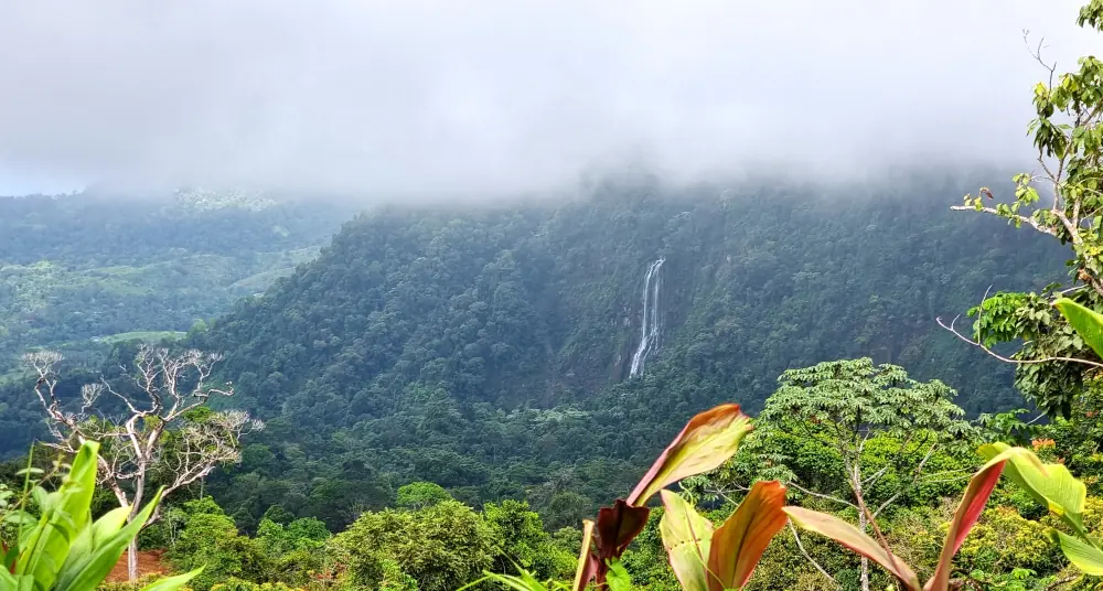 La cascade de San Luis Las Lajas vue de loin, sur une montagne boisée sous les nuages
