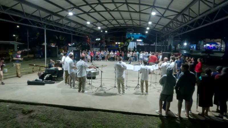 Musiciens en concert le soir sous une grande structure couverte, devant le public d'une petite ville du Costa Rica